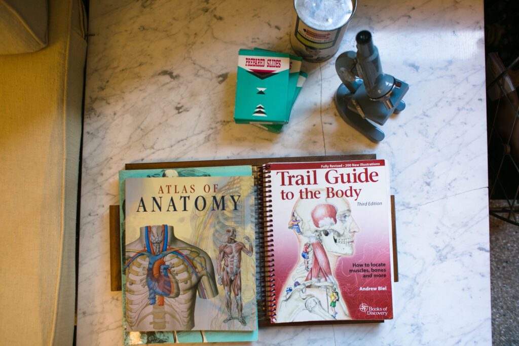 Close-up of anatomy books and tools used by Bodyworks DW therapists to study muscles, posture, and medical massage techniques.